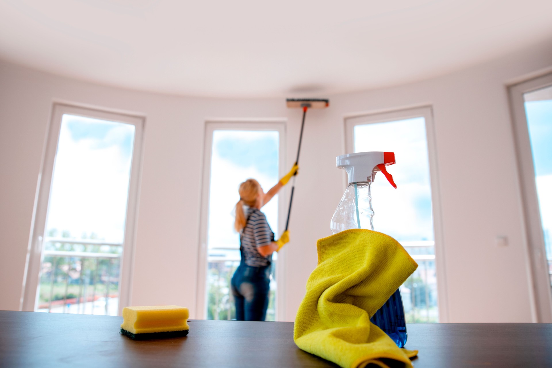 Woman dusting the ceiling with long broom